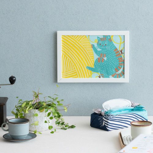 kata kataむすび　ネコと毛糸　額に入れて壁に飾っている様子