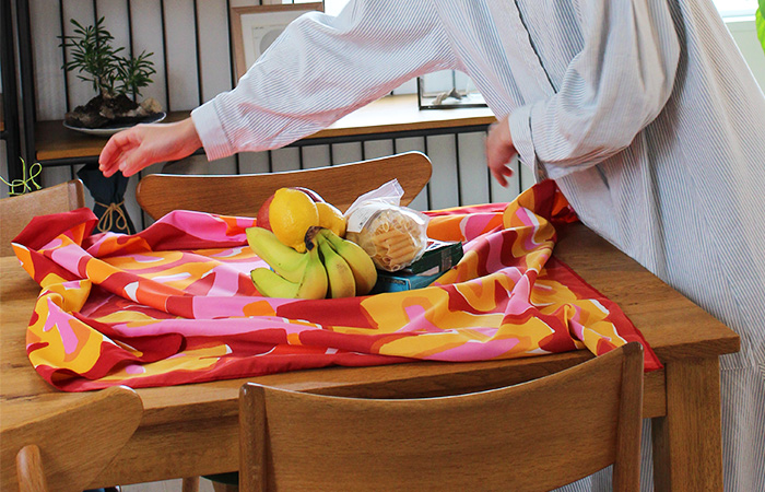 100アクアドロップリサイクル　鈴木マサル　赤い撥水加工のふろしきで果物などを包んでいる様子