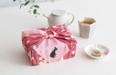 2026　春の新作　竹久夢二　梅とネコの柄のふろしきで小さなお菓子箱を包んでいる様子